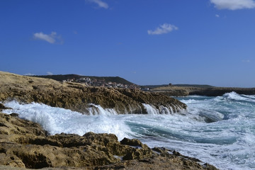 Fototapeta na wymiar Sea waves are broken up by the coastal stones in Sardinia island