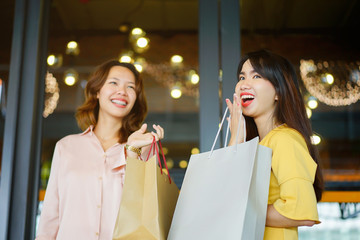 close up beautiful asian women holding smartphone with many bags at in front of mall