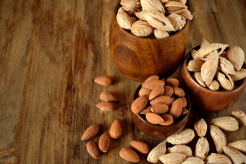 Peeled and unpeeled almond nuts in wooden bowls 