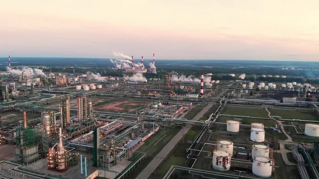 flight of the camera over the Oil refinery plant industry, Refinery factory, oil storage tank and pipeline steel with sunrise and cloudy sky background, Russia.