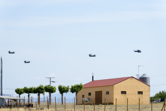 Three Boeing CH-47D Chinook helicopters flying in line with a Eurocopter Super Puma in front of the line