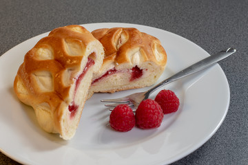 Ein Stück Himbeerkuchen dekoriert mit frischen Himbeeren auf einem weißen Kuchenteller
