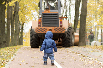Back view of baby boy opposite tractor in the park