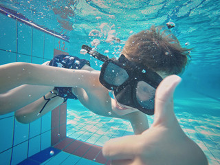 Happy young boy swim and dive underwater, kid breast stroke with fun in pool. Active healthy...