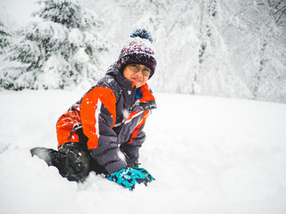 Fototapeta na wymiar Boy with red jacket playing in the snow