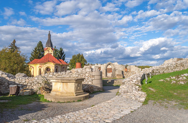 Medieval ruins of castle walls and a well with a church in the background in Miskolc, Hungary