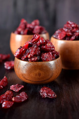 Dried cranberries in wooden bowls against the dark background