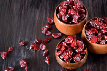 Dried cranberries in wooden bowls against the dark background