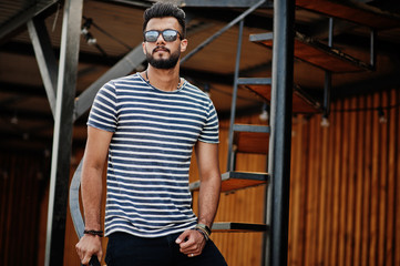 Fototapeta na wymiar Handsome tall arabian beard man model at stripped shirt posed outdoor. Fashionable arab guy at sunglasses.
