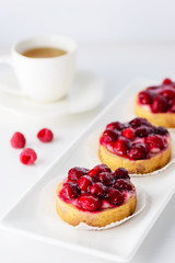 Tartlets with raspberries on a white plate