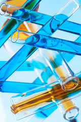 test tubes with colored liquid (yellow and blue) on light blue background