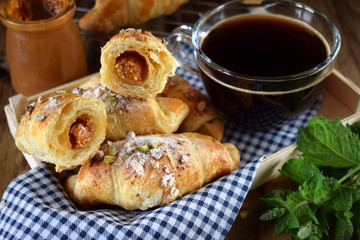 Fresh croissants sprinkled with nuts and a cup of black coffee