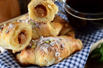 Fresh croissants sprinkled with nuts and a cup of black coffee