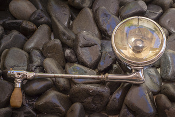 Close up shot of a antique 1930`s directional handheld spotlight used in automobiles, photographed on pebbles background, vintage concept.