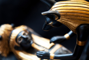 Statue of Anubis with the mummy of the deceased on a black background
