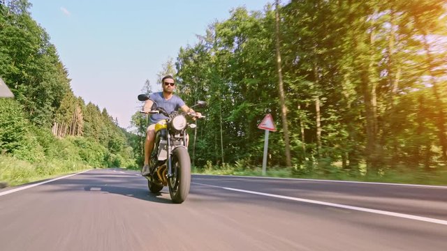 modern custom scrambler motorbike on a forest road riding. having fun driving the empty road on a motorcycle tour journey. 4k Video