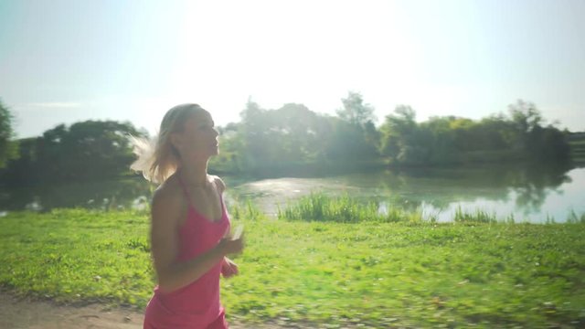 Young caucasian woman jogging in public park near the river