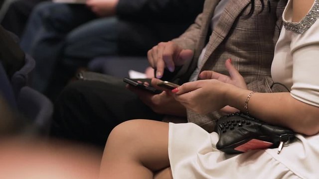 Close up of a mans and womans hands. Stock. Man and a woman sitting at a conference with phones