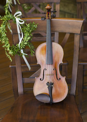 Beautiful violin on a wooden chair. Musical instrument. Wedding decorations