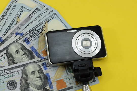 money (dollars) and a photo camera on a yellow background