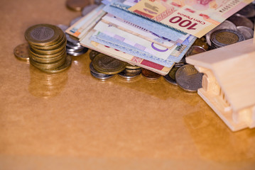 Mortgage house loan, real estate tax, macro financial Concept, Scandinavian house model with pile of banknotes and coins money on brown wooden shiny surface table, with copy space.