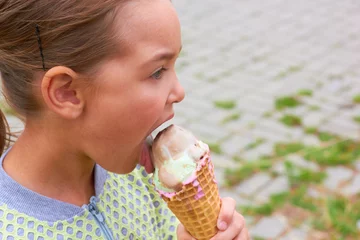 Fotobehang A little girl is eating ice cream. © valeriya