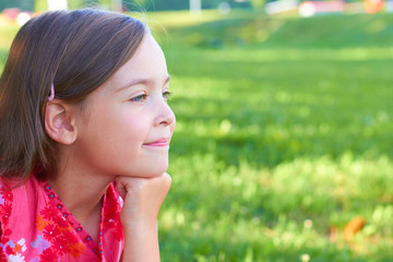 A small Caucasian girl with long hair is resting in the park.