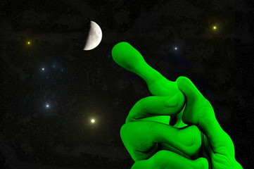 Fototapeta na wymiar universe - green alien hand with outstretched finger pointing to the moon and the stars