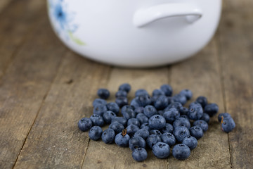 Ripe blueberry fruit in a container on a wooden kitchen table. Fruit prepared for dessert.