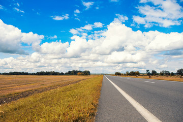 Obraz premium Beautiful and sunny road landscape with sky clouds and yellow fields