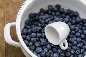 Ripe blueberry fruit in a container on a wooden kitchen table. Fruit prepared for dessert.