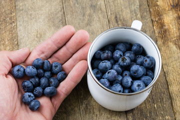 Ripe blueberry fruit in a container on a wooden kitchen table. Fruit prepared for dessert.