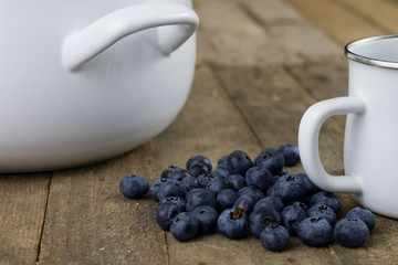 Ripe blueberry fruit in a container on a wooden kitchen table. Fruit prepared for dessert.