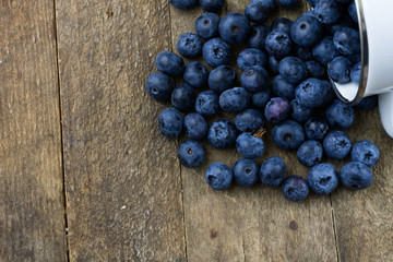 Ripe blueberry fruit in a container on a wooden kitchen table. Fruit prepared for dessert.
