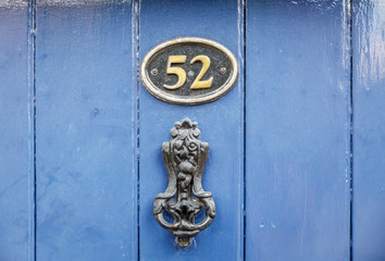 View of the knob of a blue wooden door with the number 52