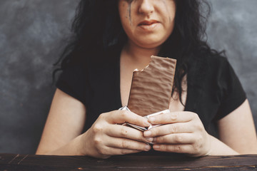 Food addiction, dieting concept. Young overweight woman fed up with diets eating chocolate greedily...