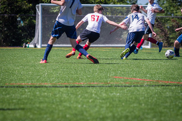 Teenage soccer players competing for the ball in front of the goal