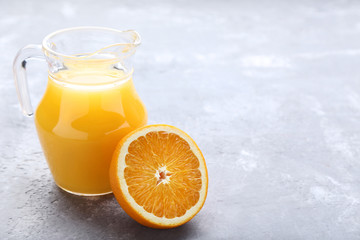 Orange fruit with jug of juice on grey wooden table