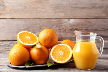 Orange fruit in tray with jug of juice on grey wooden table