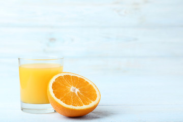 Orange fruit with glass of juice on white wooden table