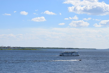 a small white steamer floating on the river on a warm summer day and the blue sky with clouds