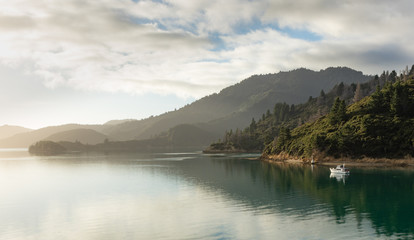 Mystical view over the water during morning sail. Sun rays peaking through. Quiet, relaxing. Mountains, water, sky..