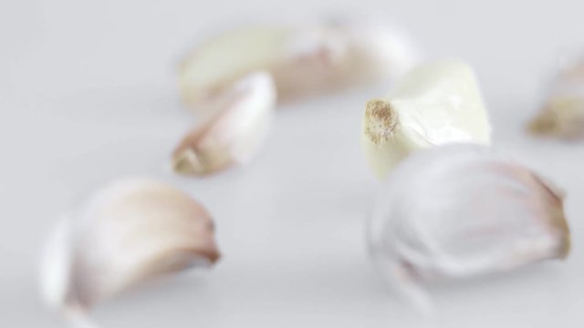 Macro shot of many pieces of garlic is on a white table with white background. Preparing for cooking.