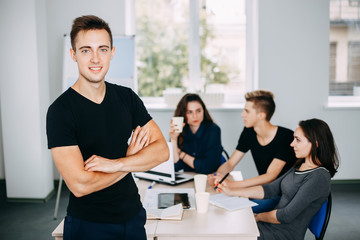 I am the part of cohesive team. Young successful man specialist portrait with colleagues meeting behind him. friendly atmosphere, communication and comradery