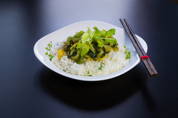 Asian food on rice. Vegetable meal. Vegetarian, healthy, rich, tasty. Black background, rice, vegetable, spice. Chopstick.