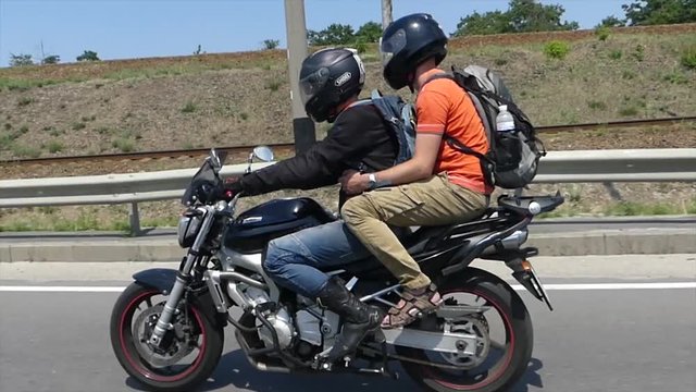 A motorcyclist drives a passenger on a motorcycle.