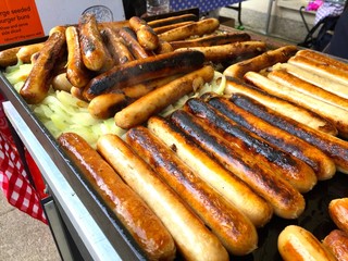 Hotdogs and fried onions on a grill.