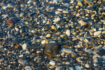 pebble stones on the sea beach, the rolling waves of the sea with foam