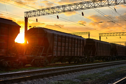 railroad infrastructure during beautiful sunset and colorful sky, railcar for dry cargo, transportation and industrial concept