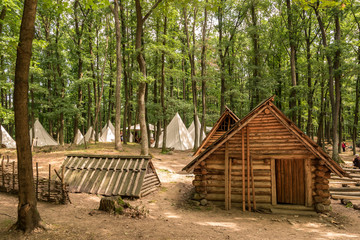 Early medieval village with wooden cottages and white tents in a forest. Bojna, Slovakia. Velkomoravské hradiště v Bojné, Slovensko.